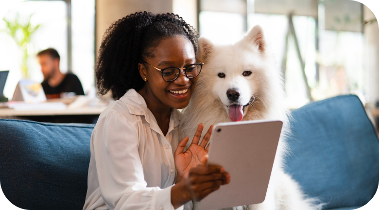 Girl holding a small dog working on a laptop