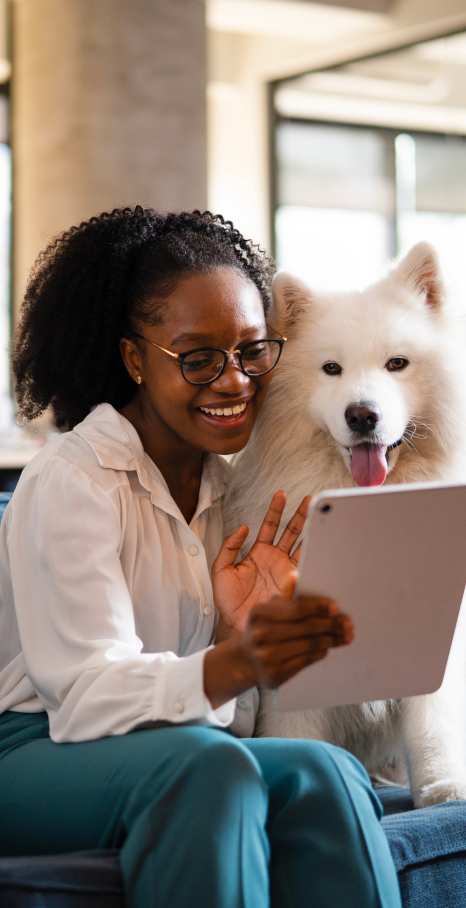 Girl holding a small dog working on a laptop