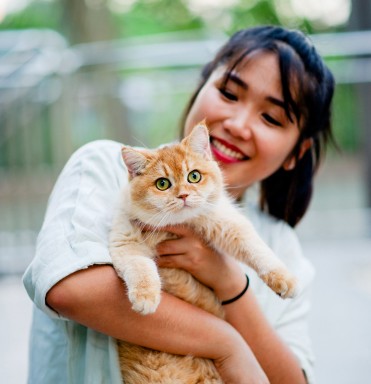 Happy girl holding an orange cat