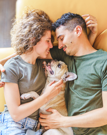 Couple laying on the bed with a small brown dog